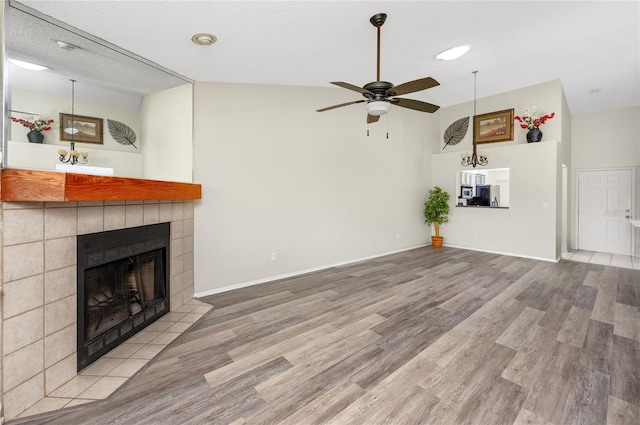 unfurnished living room featuring a ceiling fan, a fireplace, baseboards, and wood finished floors