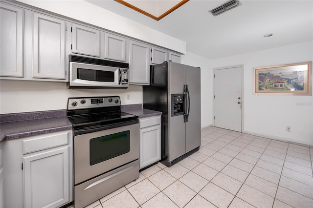 kitchen with appliances with stainless steel finishes, dark countertops, visible vents, and light tile patterned flooring