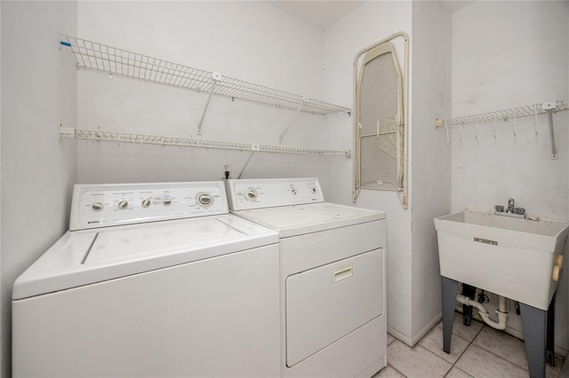 washroom featuring laundry area, washer and clothes dryer, light tile patterned flooring, and a sink