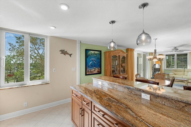 kitchen featuring light stone counters, pendant lighting, ceiling fan, and light tile patterned flooring