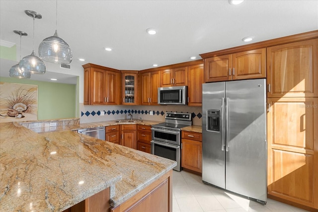 kitchen with pendant lighting, backsplash, stainless steel appliances, light stone countertops, and kitchen peninsula