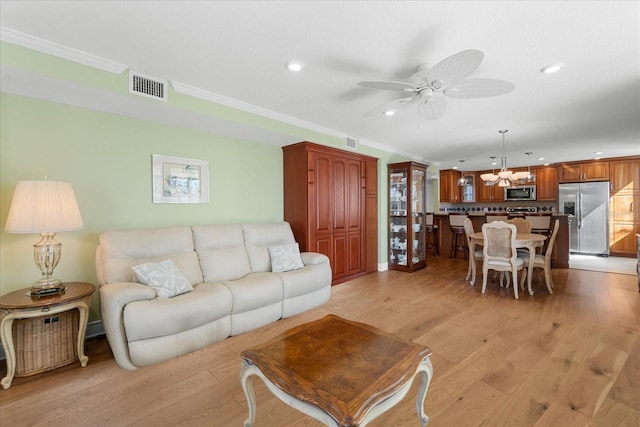 living room with crown molding, ceiling fan with notable chandelier, and light hardwood / wood-style floors