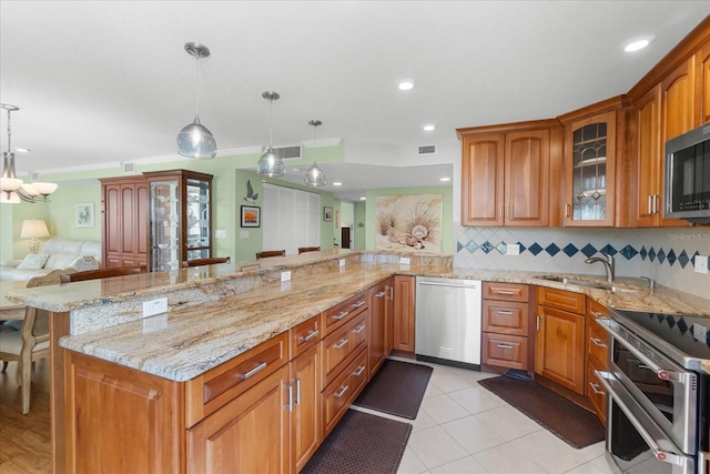 kitchen featuring sink, a breakfast bar area, decorative light fixtures, appliances with stainless steel finishes, and kitchen peninsula