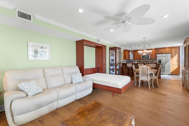 living room with crown molding, ceiling fan with notable chandelier, and light hardwood / wood-style floors