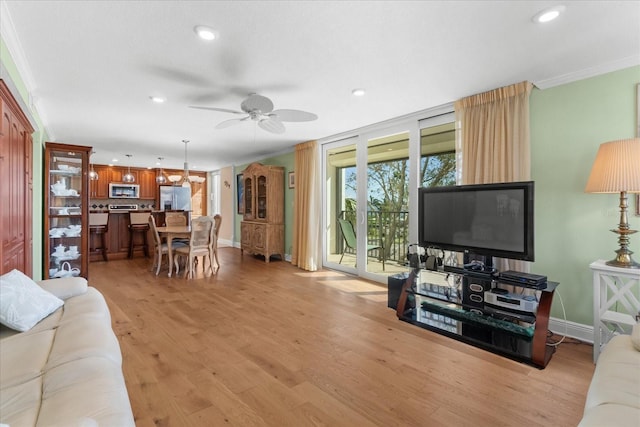 living room featuring crown molding, ceiling fan, and light wood-type flooring