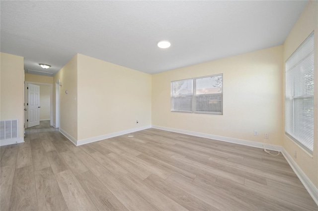 empty room featuring a textured ceiling and light hardwood / wood-style floors