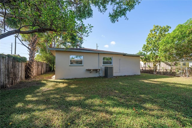 rear view of house featuring central AC and a yard