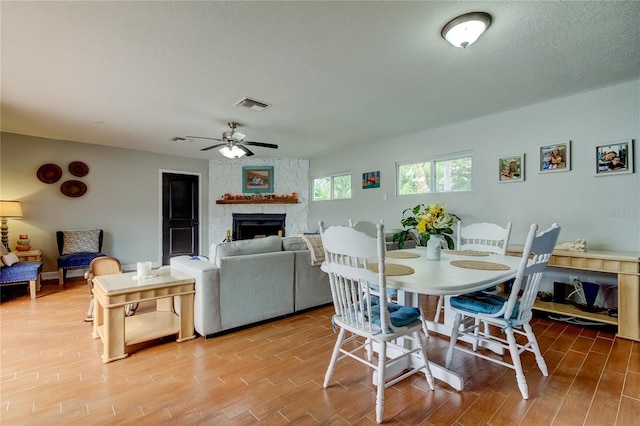 dining area with ceiling fan and a fireplace