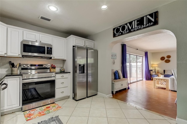 kitchen featuring decorative backsplash, light tile patterned flooring, white cabinetry, and appliances with stainless steel finishes