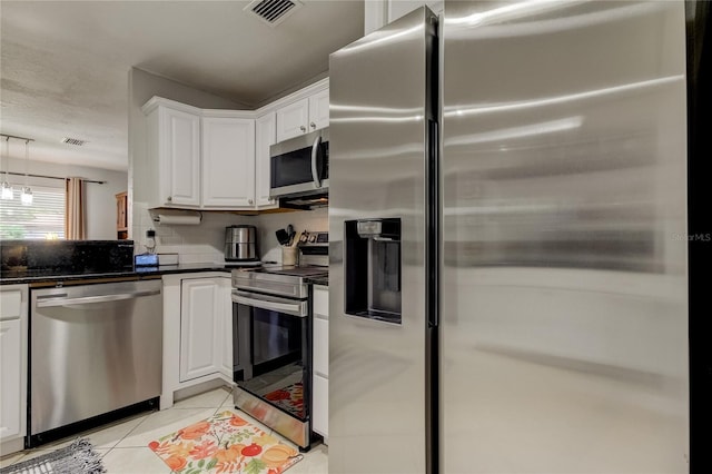 kitchen with backsplash, white cabinets, light tile patterned floors, decorative light fixtures, and stainless steel appliances