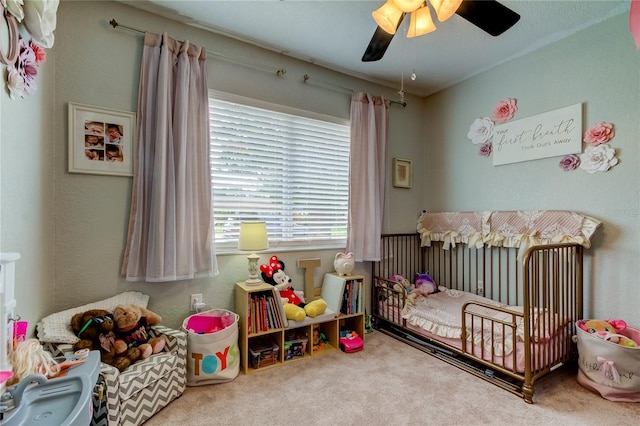 bedroom featuring carpet, ceiling fan, and a crib