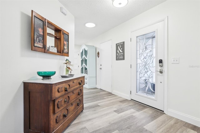 foyer entrance featuring a textured ceiling and light wood-type flooring