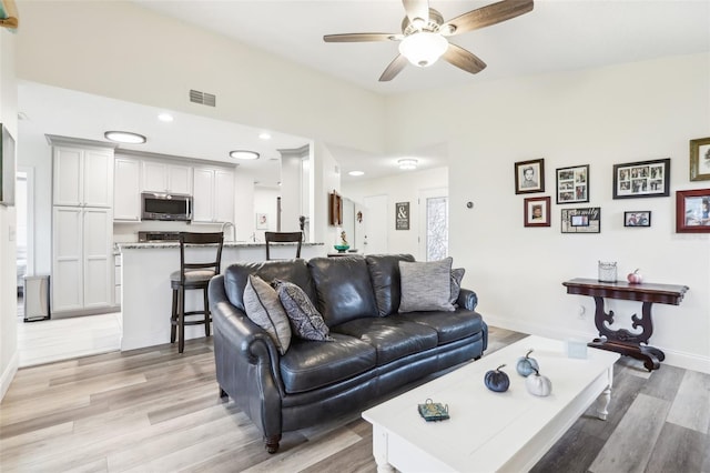 living room featuring light wood-type flooring and ceiling fan