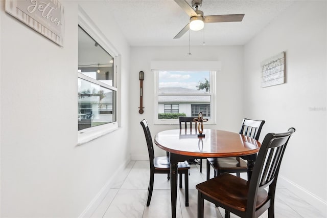 dining space featuring ceiling fan and a textured ceiling