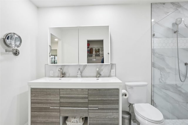 bathroom with toilet, vanity, and tiled shower