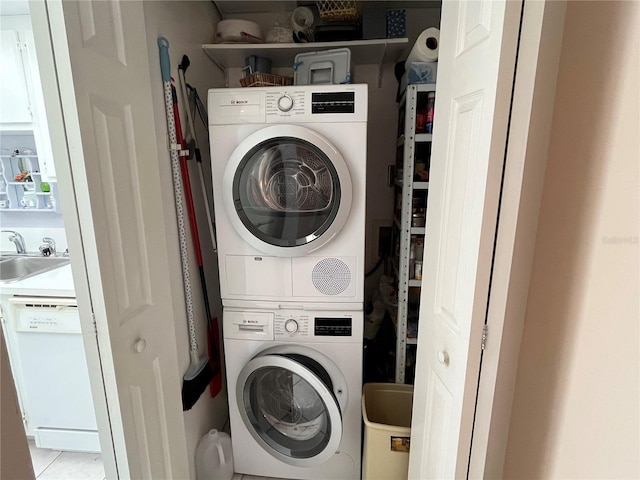 laundry room with light tile patterned floors, stacked washer / dryer, and sink