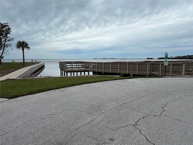 view of dock with a lawn and a water view