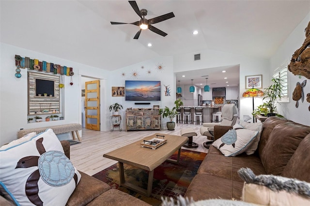 living room with hardwood / wood-style flooring, ceiling fan, and vaulted ceiling