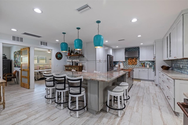 kitchen featuring pendant lighting, a large island with sink, and light hardwood / wood-style floors