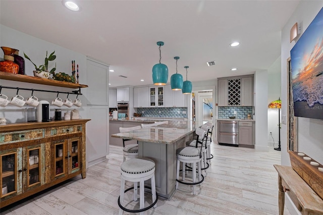 kitchen featuring tasteful backsplash, pendant lighting, light hardwood / wood-style floors, and white cabinets