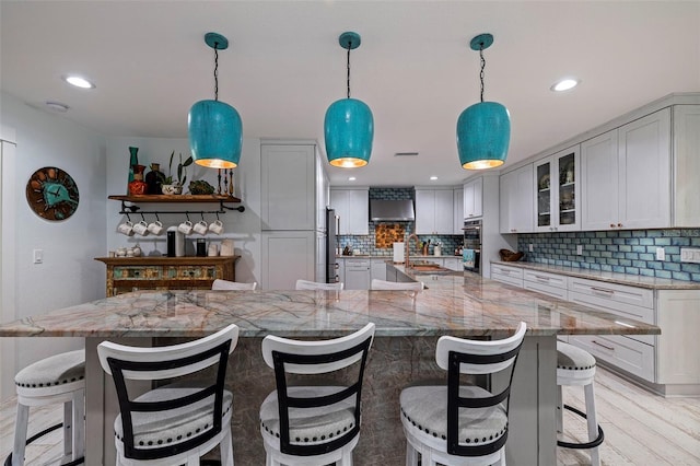 kitchen with light stone countertops, decorative light fixtures, decorative backsplash, and light hardwood / wood-style flooring