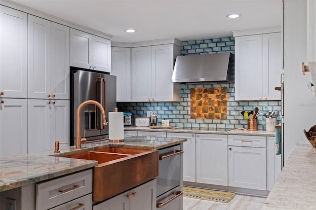 kitchen with light stone countertops, decorative backsplash, light hardwood / wood-style floors, black electric cooktop, and wall chimney exhaust hood