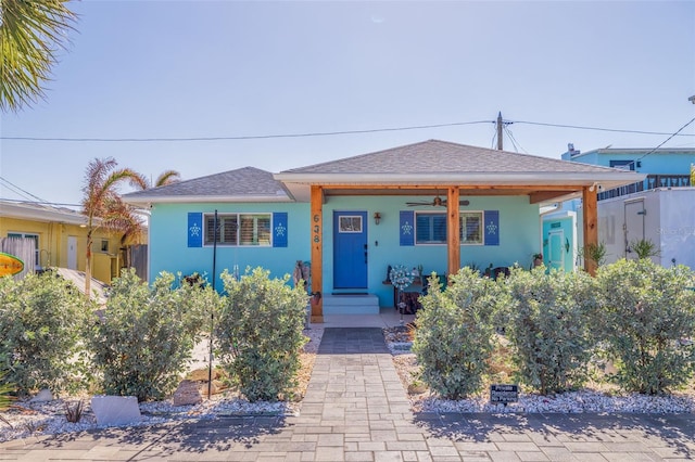 bungalow with a shingled roof, a ceiling fan, fence, and stucco siding