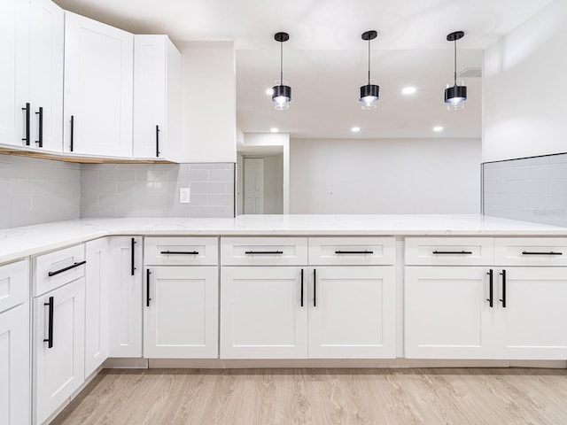 kitchen featuring light hardwood / wood-style floors, white cabinetry, decorative light fixtures, and light stone counters