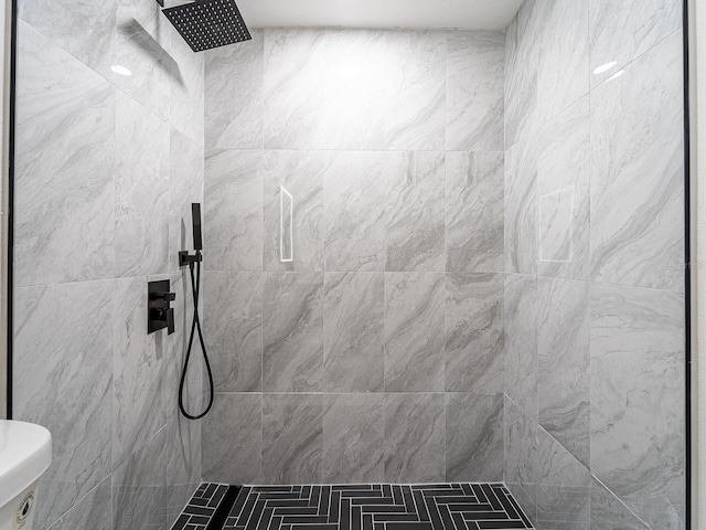 bathroom with tiled shower and toilet