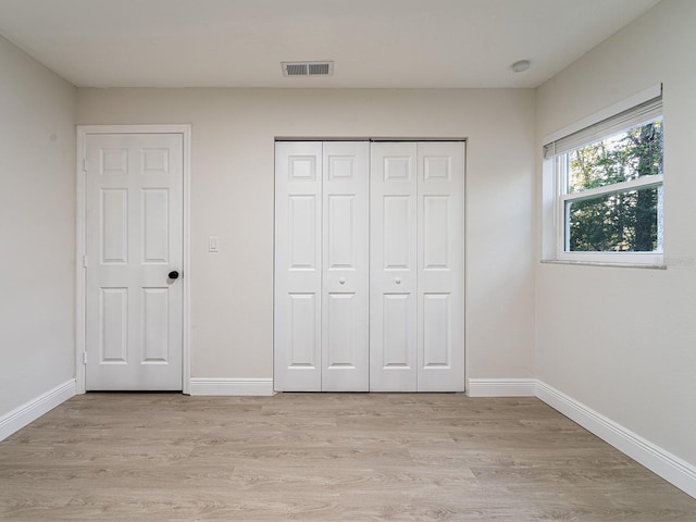 unfurnished bedroom with light hardwood / wood-style floors and a closet