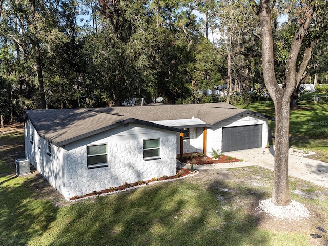 view of front of home with central AC unit, a garage, and a front lawn