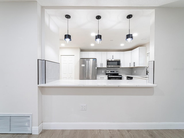 kitchen with stainless steel appliances, white cabinetry, light hardwood / wood-style flooring, and kitchen peninsula