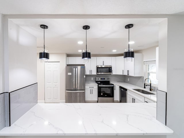 kitchen with white cabinetry, appliances with stainless steel finishes, and decorative light fixtures