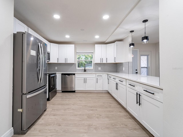 kitchen with stainless steel appliances, a wealth of natural light, white cabinets, and light hardwood / wood-style flooring