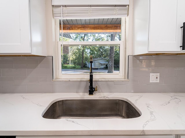 details with sink, tasteful backsplash, and light stone countertops