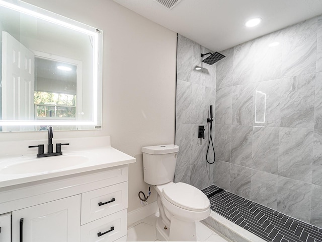 bathroom with toilet, vanity, tile patterned floors, and a tile shower