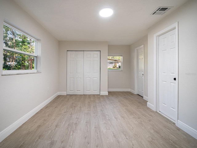 unfurnished bedroom with light hardwood / wood-style floors and two closets