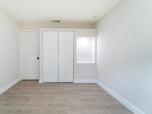 unfurnished bedroom with light hardwood / wood-style flooring and a closet