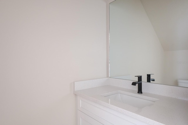 bathroom with toilet, vaulted ceiling, and vanity