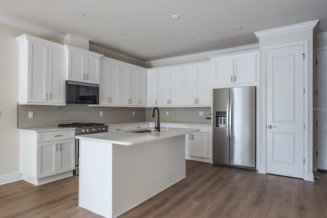 kitchen with stainless steel appliances, a kitchen island with sink, white cabinetry, and sink