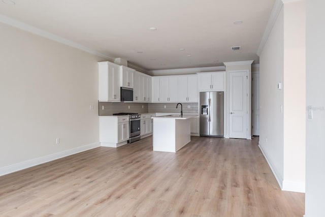 kitchen featuring an island with sink, tasteful backsplash, white cabinets, appliances with stainless steel finishes, and ornamental molding