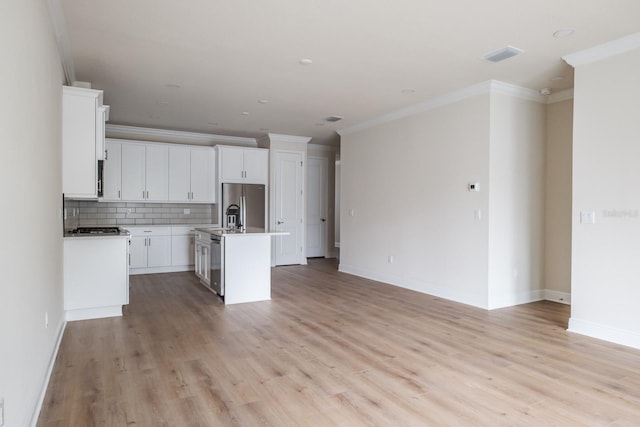 kitchen featuring white cabinets, a kitchen island with sink, ornamental molding, and appliances with stainless steel finishes