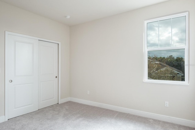 unfurnished bedroom featuring a closet, multiple windows, and light colored carpet