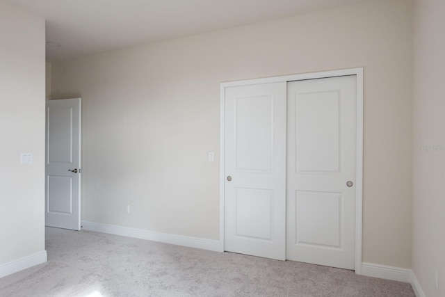 unfurnished bedroom featuring a closet and light carpet