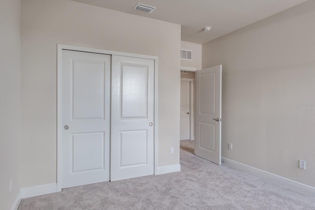 unfurnished bedroom featuring a closet and light colored carpet