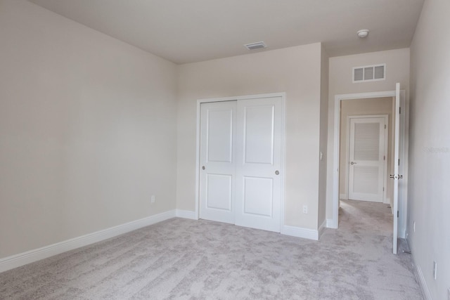 unfurnished bedroom with light colored carpet and a closet