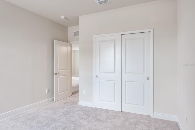 unfurnished bedroom with light colored carpet and a closet