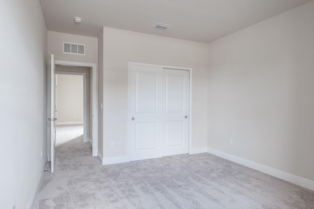 unfurnished bedroom featuring a closet and light carpet