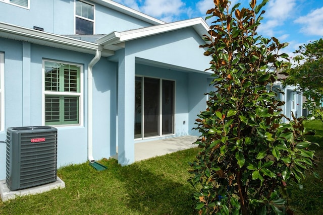 view of side of home with cooling unit and a yard