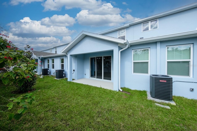 rear view of property featuring central AC unit and a lawn